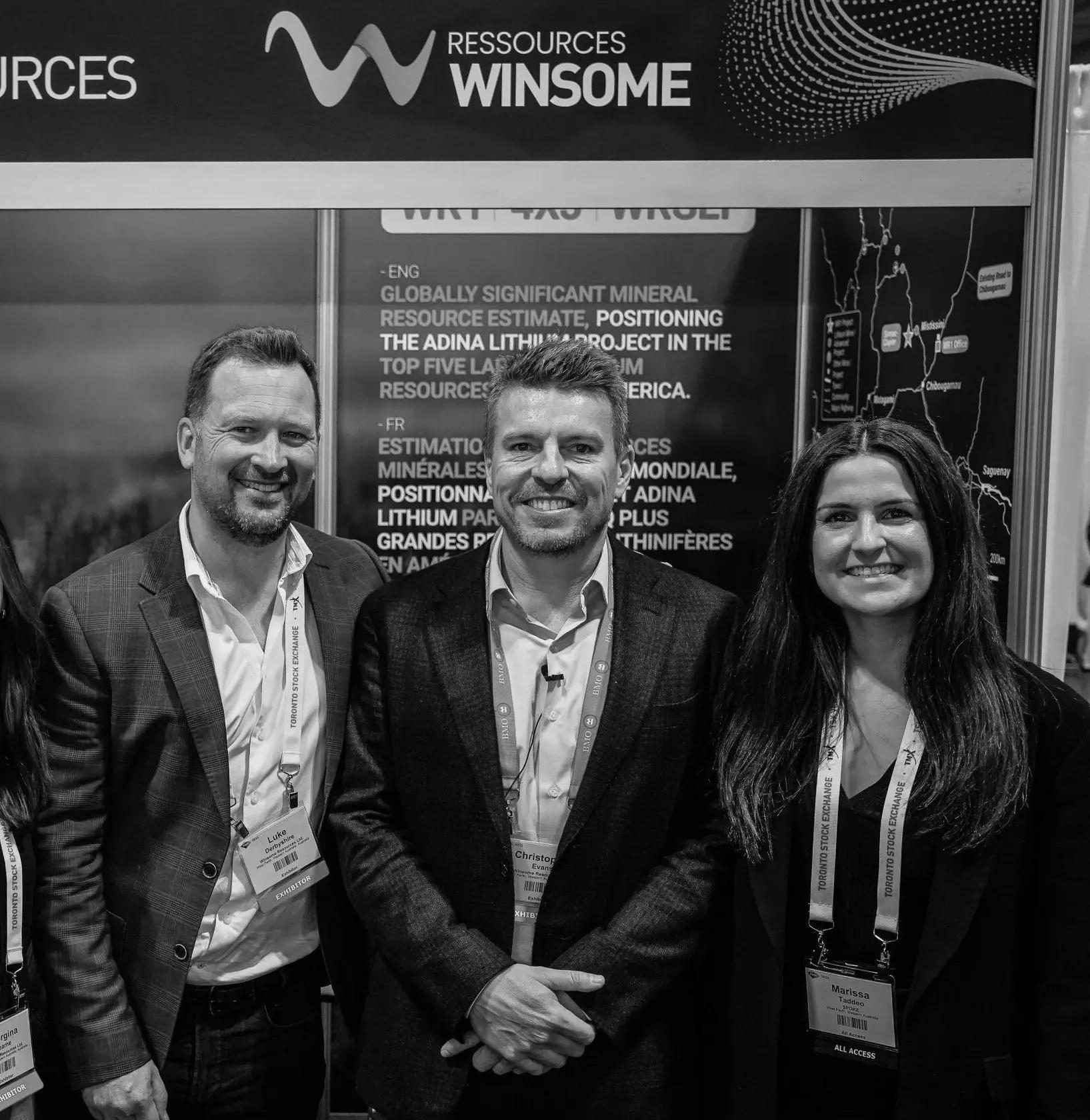 Three people at the Winsome Resources stand at PDAC, beside a panel describing the Adina lithium project.