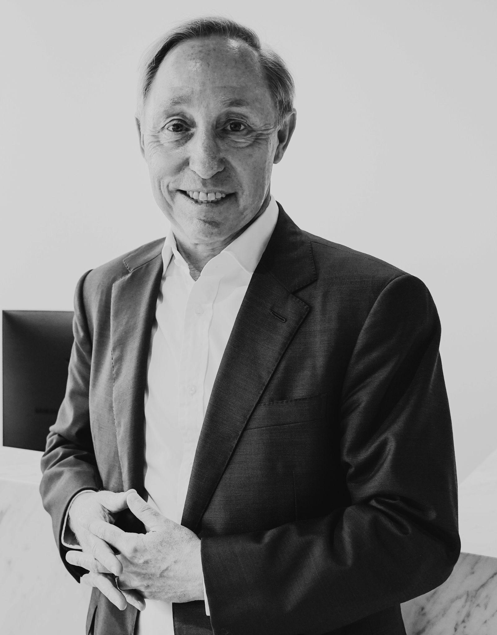 A studio portrait of a man in a dark suit against a plain background.