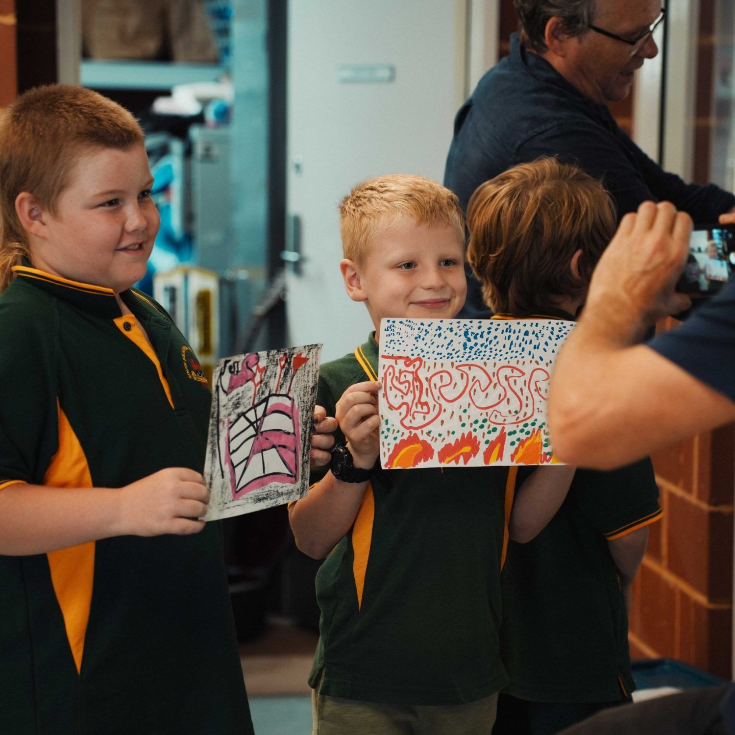 Primary school students holding the artwork they created in the Gold Fields creative workshops.