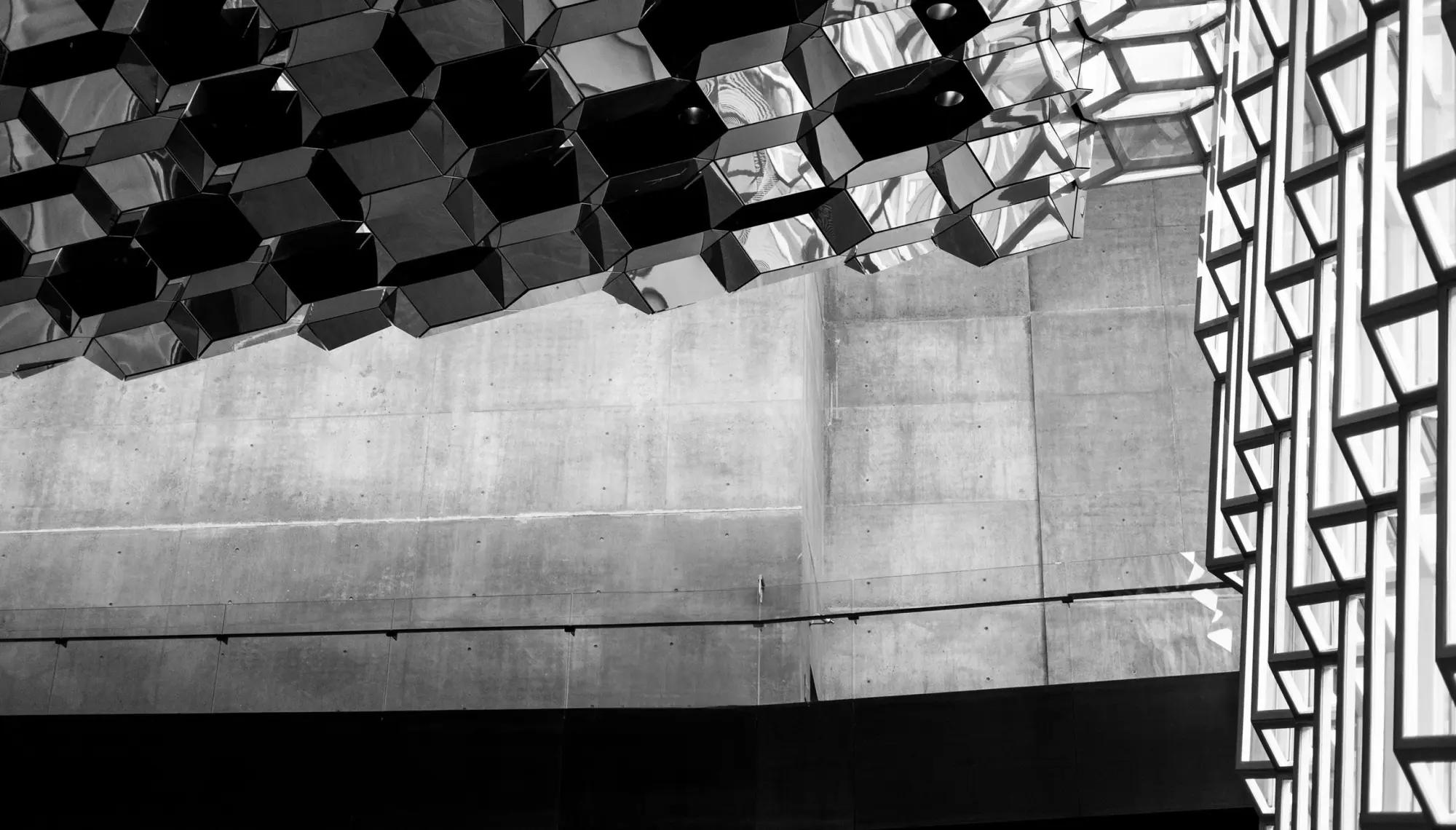 Angular mirrored panels above a concrete wall inside a modern building.