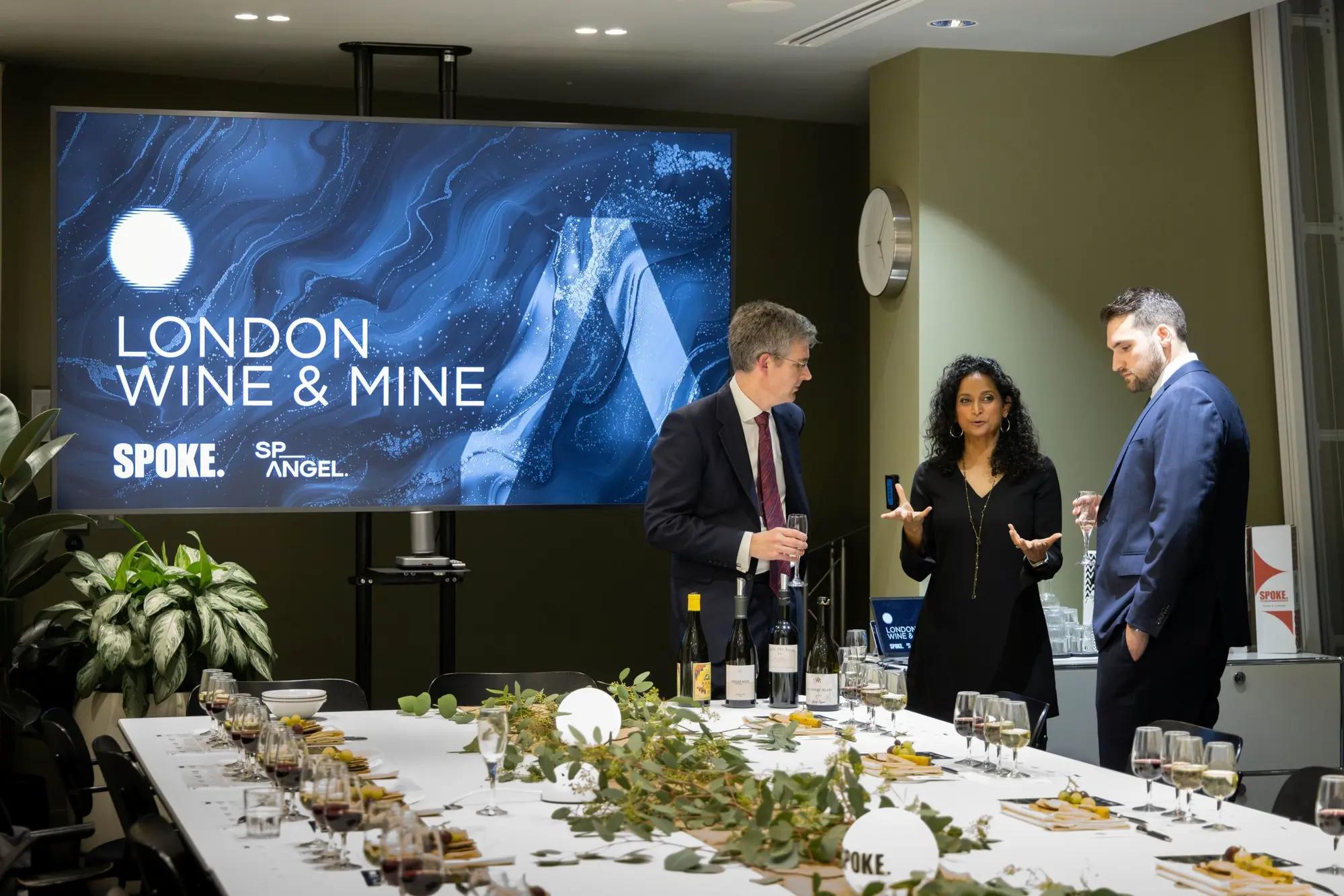 Guests talking beside a London Wine and Mine screen at a set table.