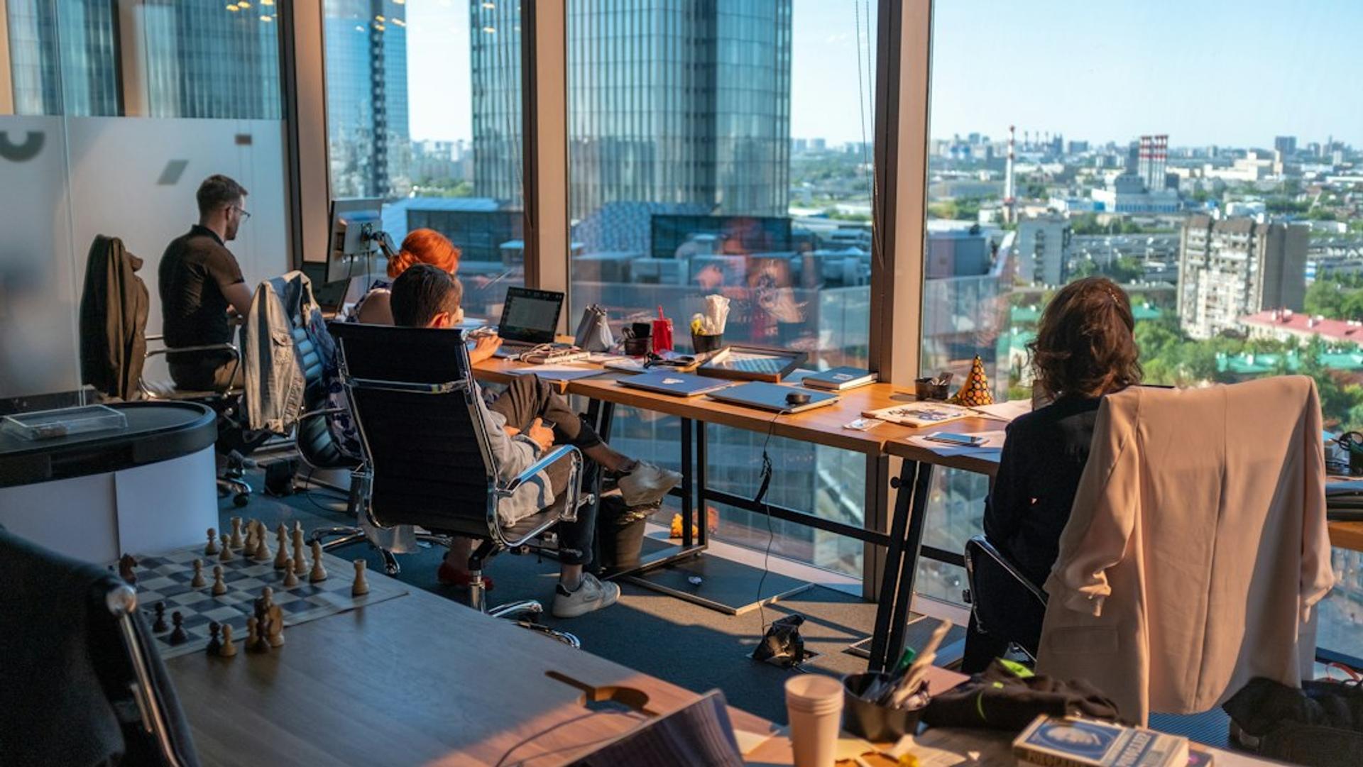 Tim bekerja di kantor lantai tinggi berpemandangan kota sambil menyusun laporan bulanan SEO