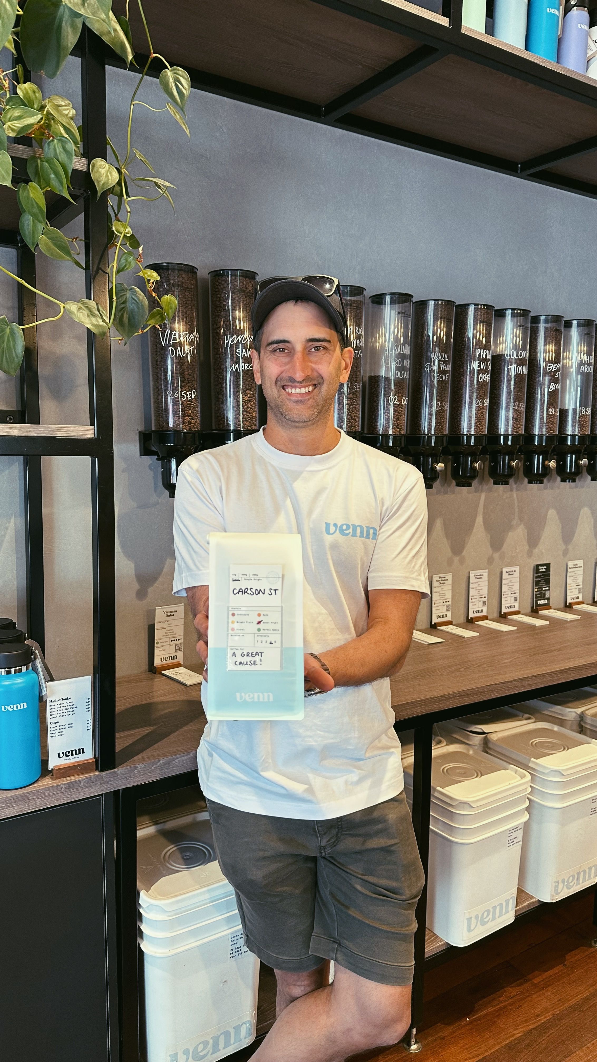 Matt is holding a white and blue bag of coffee beans with a tag that reads 'Carson St.'