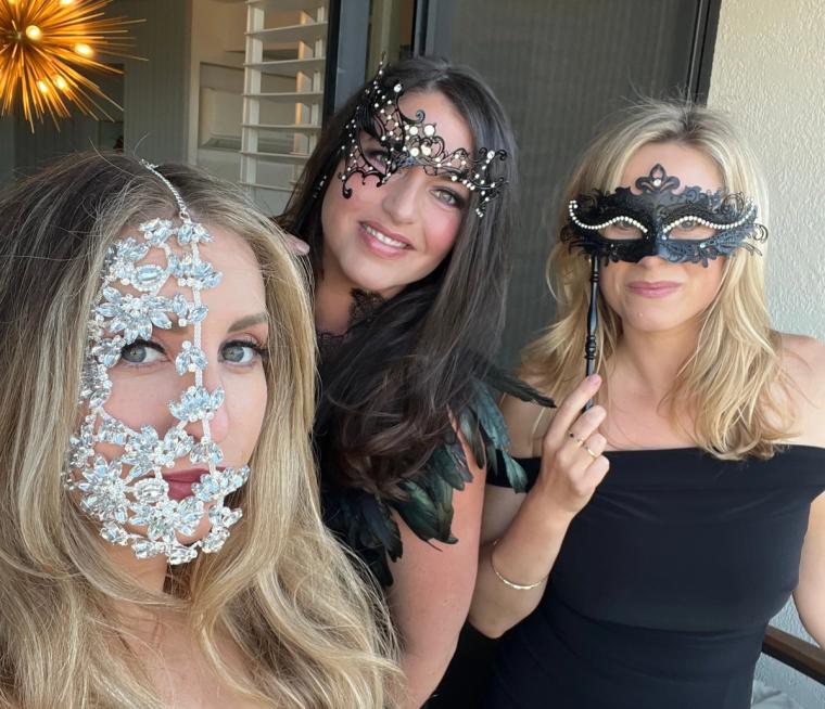 Three guests posing in bejeweled masquerade masks at the Enchanted Garden-themed gala