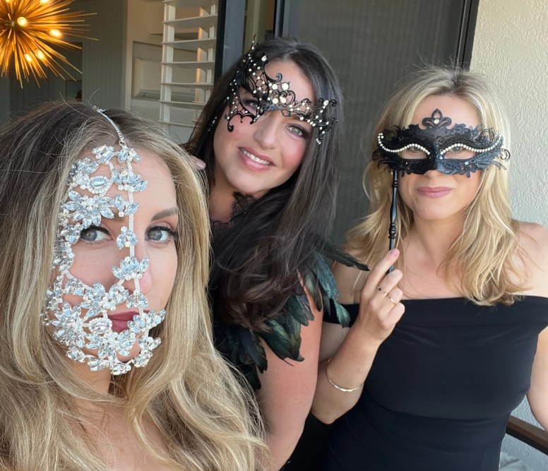 Three guests posing in bejeweled masquerade masks at the Enchanted Garden-themed gala