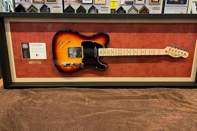 The autographed sunburst guitar Nathan won at the 2024 Hope for Heroes Gala, mounted in a shadow-box frame