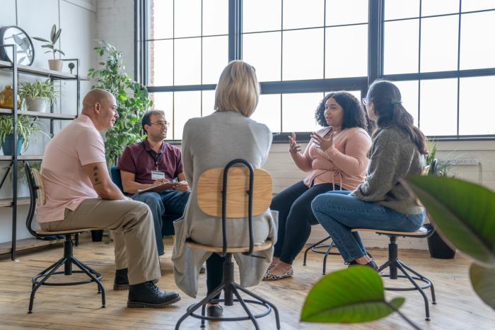 A small peer support group sitting together in a circle in a sunlit room