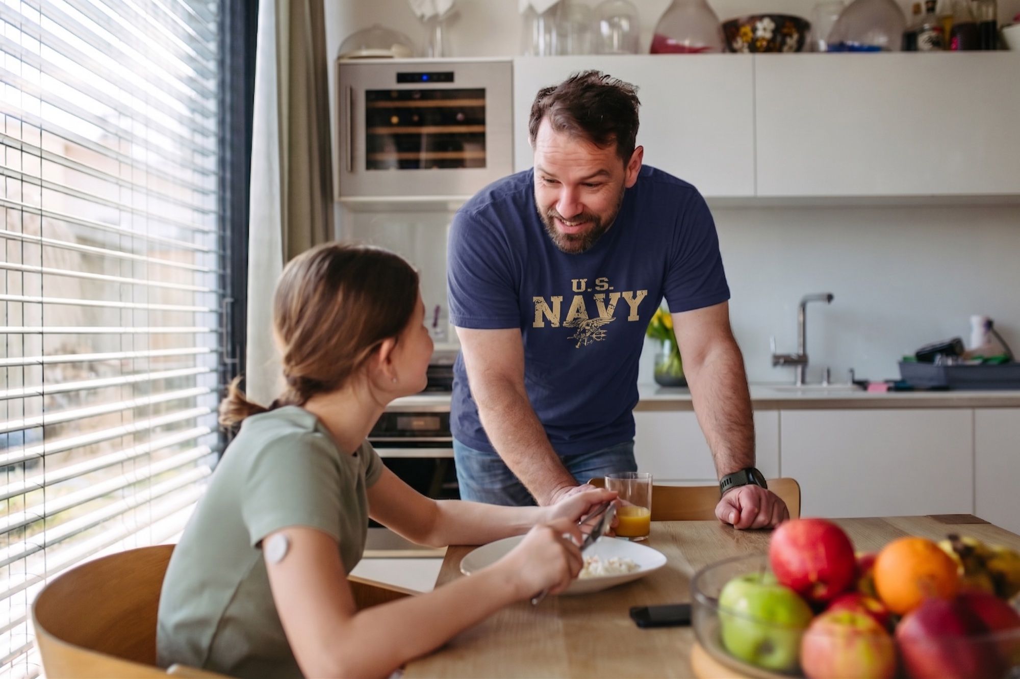 A Navy Veteran shares breakfast with his daughter at their kitchen table