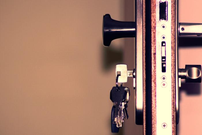 A set of keys hanging in the lock of an apartment door