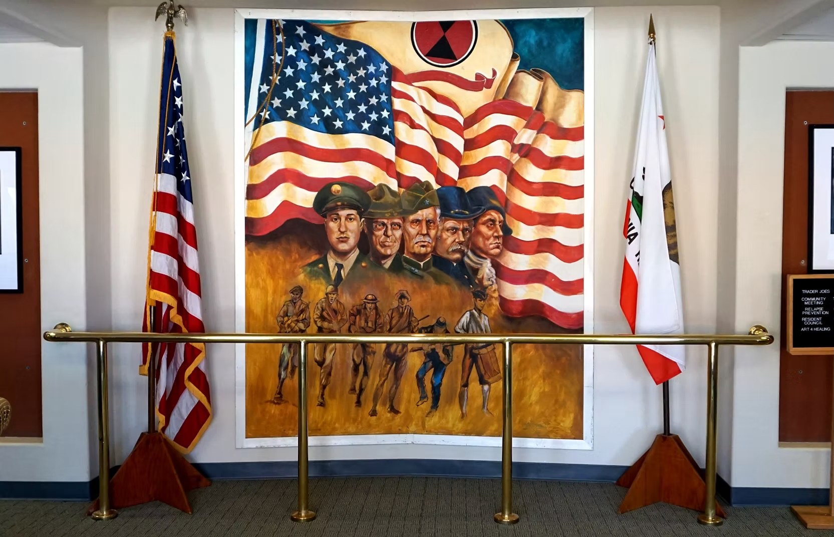 Mural honoring American servicemembers across generations beneath the U.S. flag in the VTC lobby