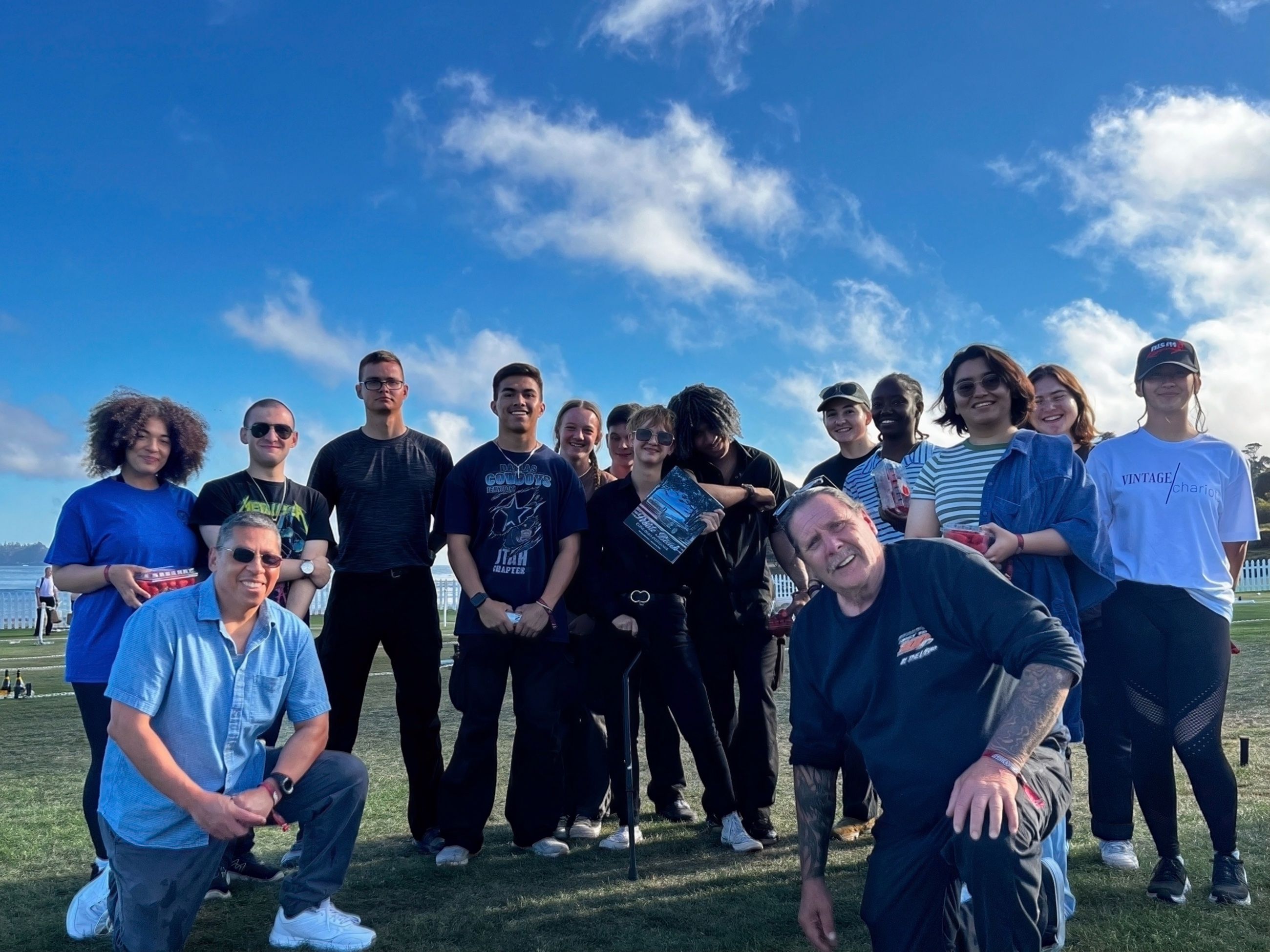 A group of volunteers gathered on a grass field at a community event above Monterey Bay