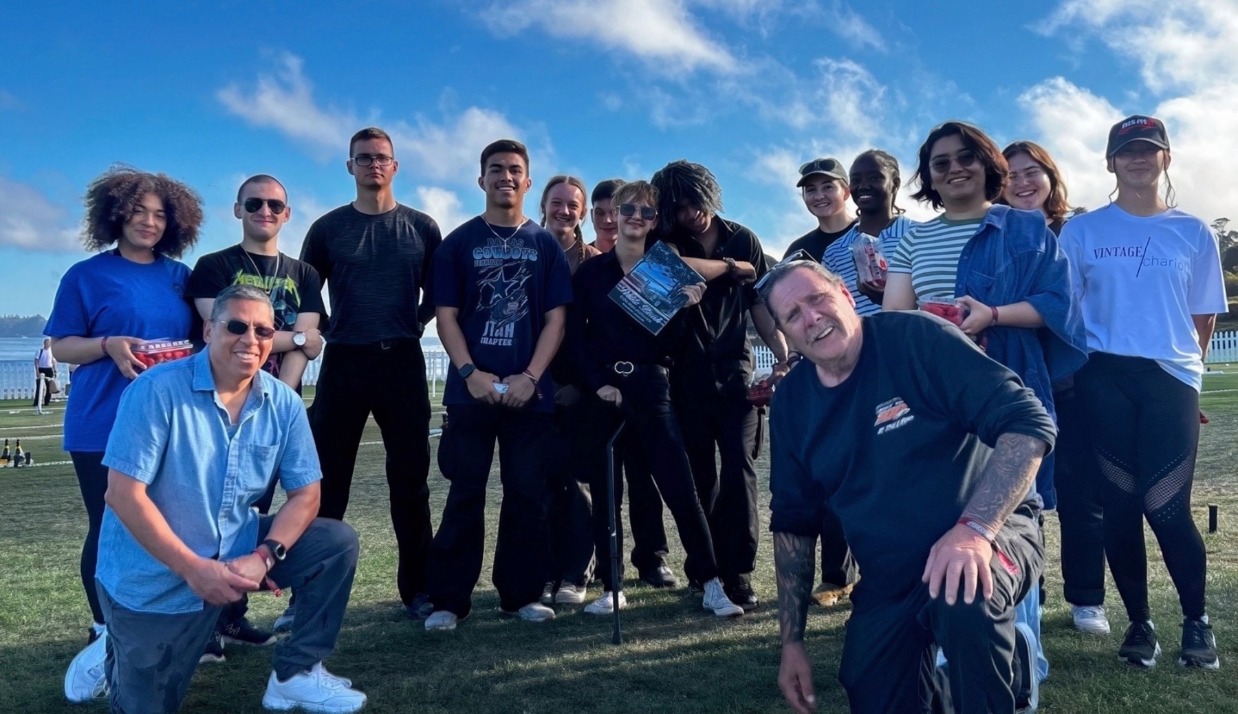 A group of volunteers gathered on a grass field at a community event above Monterey Bay