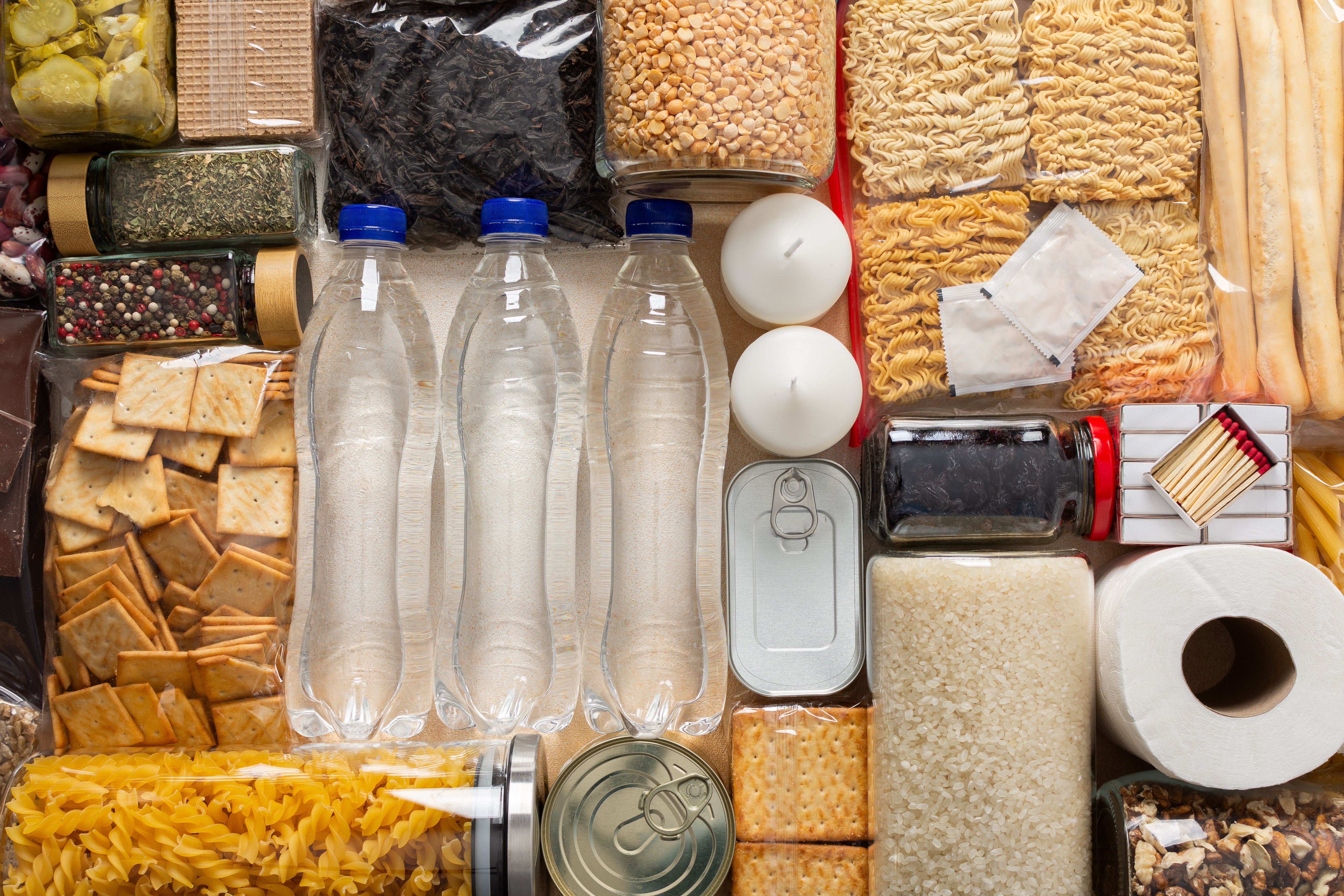 Pantry staples laid out — water, rice, pasta, canned goods, and essentials