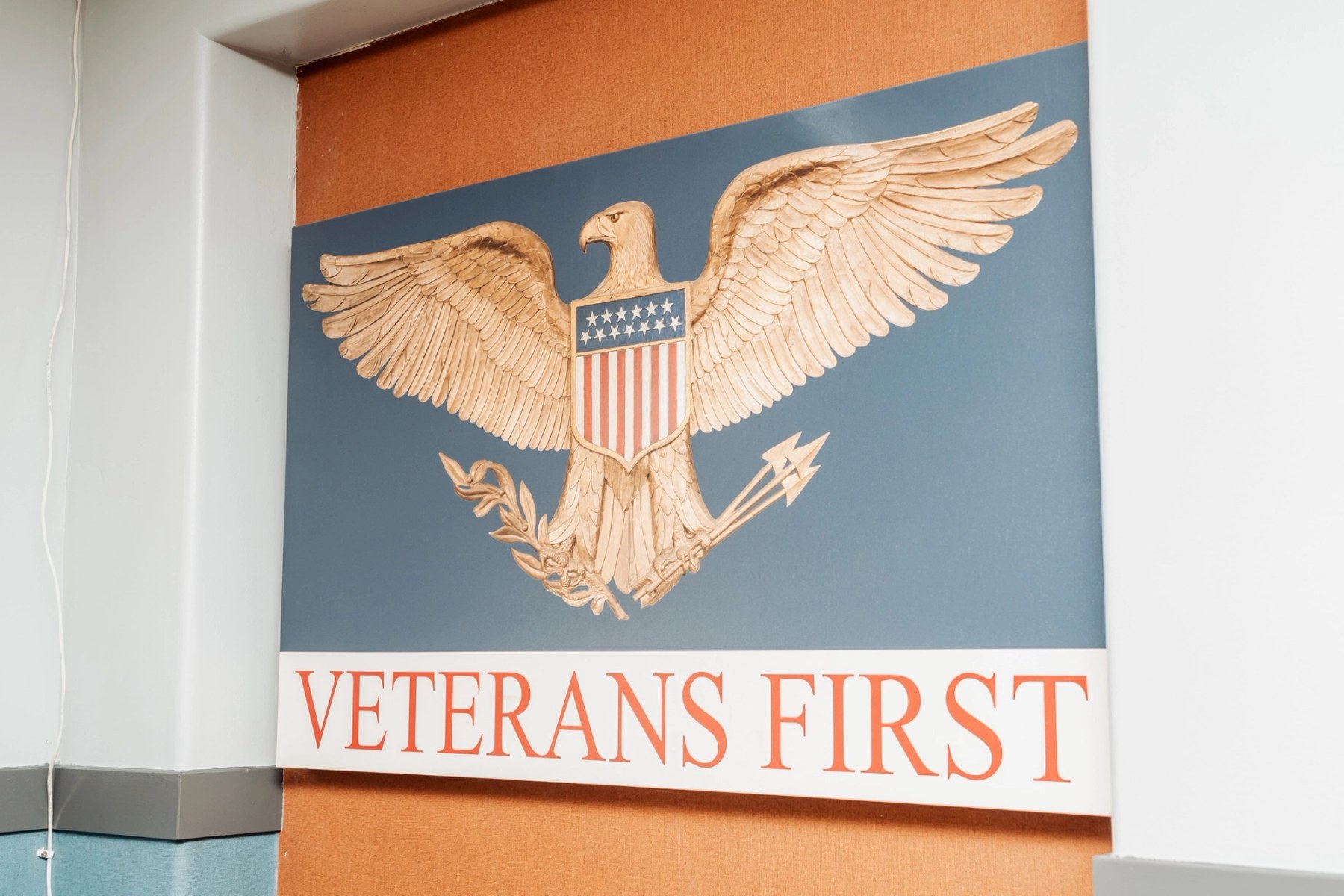 The "Veterans First" sign at the VTC campus — a carved gold eagle with a stars-and-stripes shield