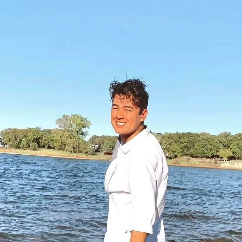 Nathan smiling at the edge of a lake on a sunny day