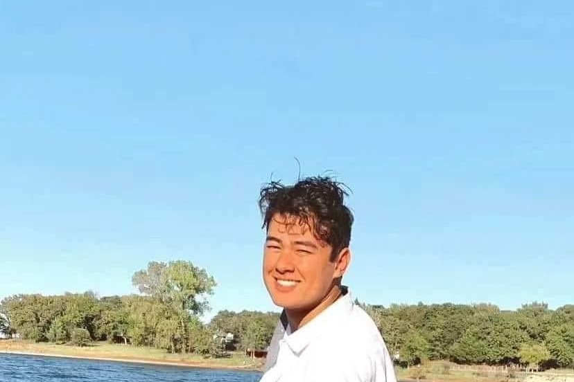 Nathan smiling at the edge of a lake on a sunny day