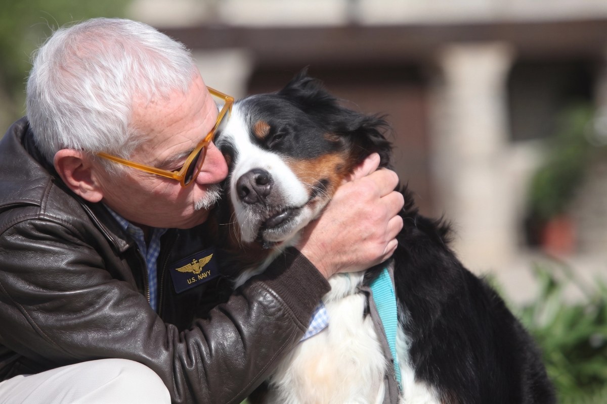 A Navy Veteran embraces his dog outside on a sunny day