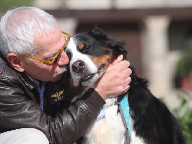 A Navy Veteran embraces his dog outside on a sunny day