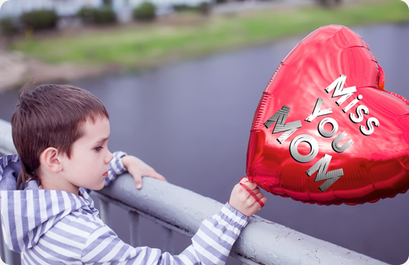 Boy holding a balloon that says "miss you mom"