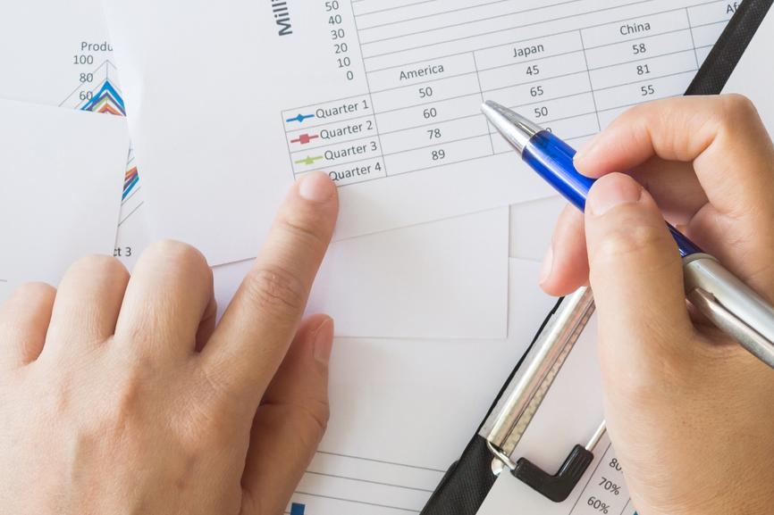 A person writing on a clipboard with a pen.
