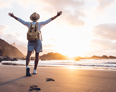 A man joyfully walks on the beach, extending his arms outward