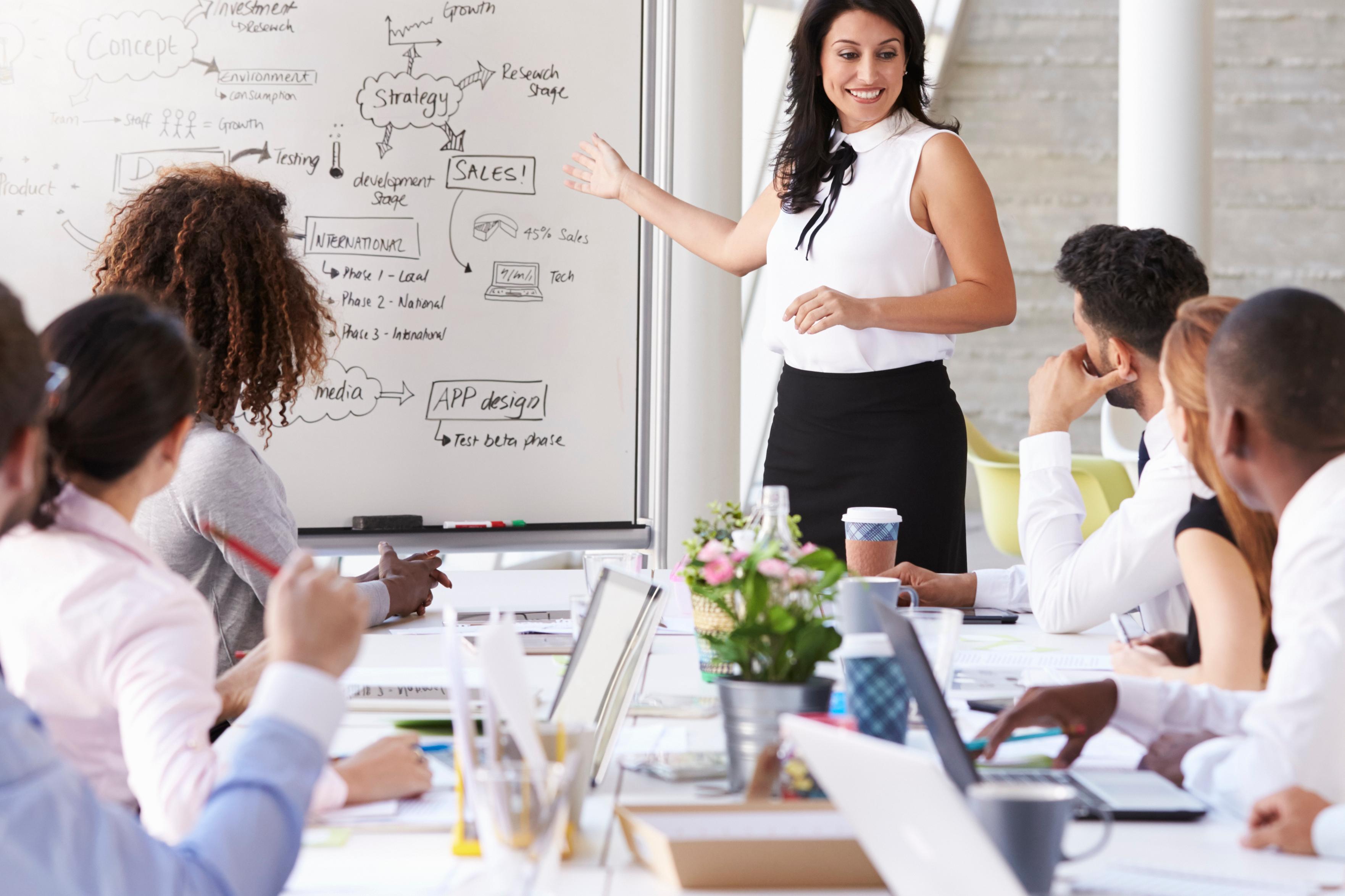A professional businesswoman confidently presenting to her colleagues during a meeting.