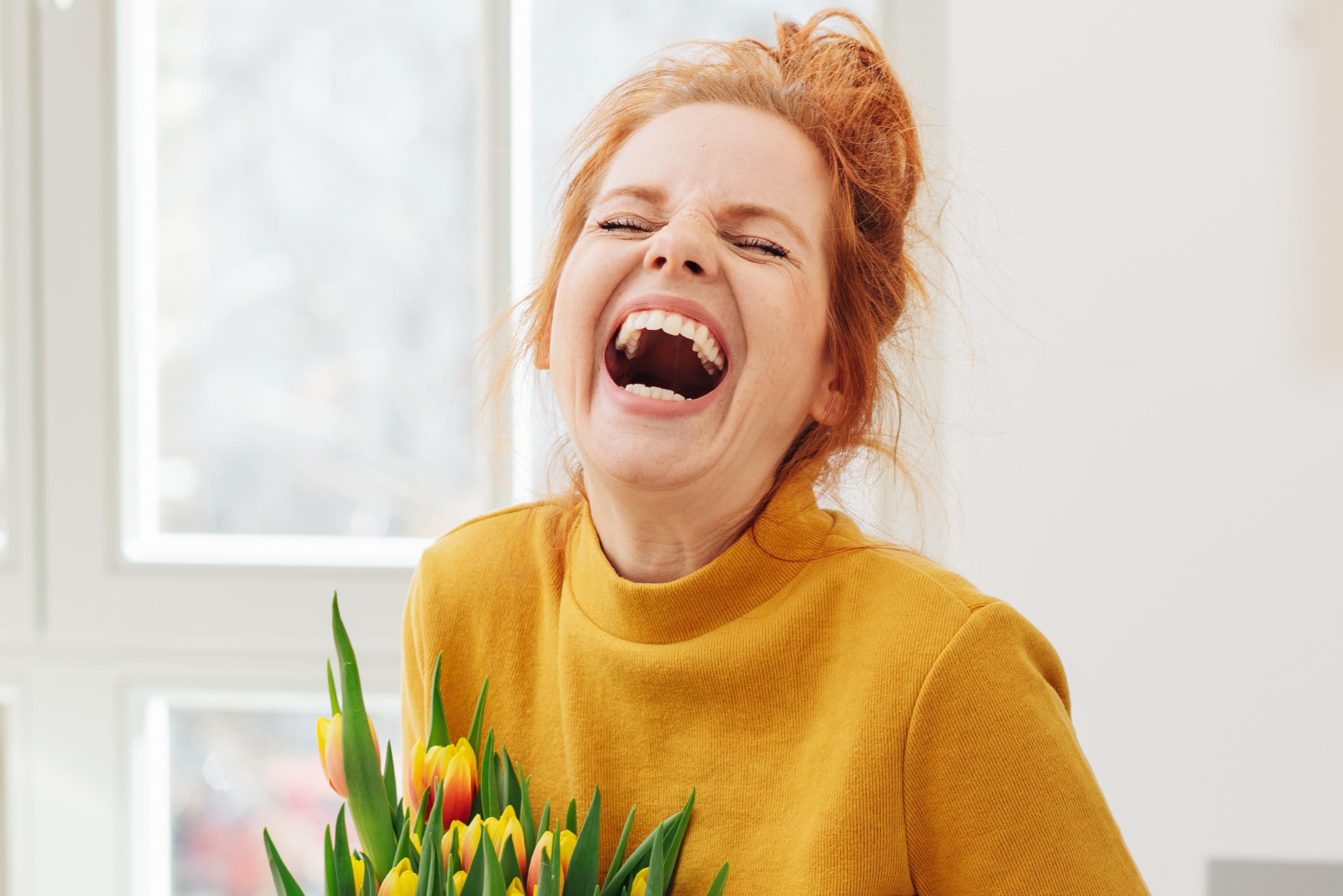 Woman holding tulips in a vase, laughing joyfully
