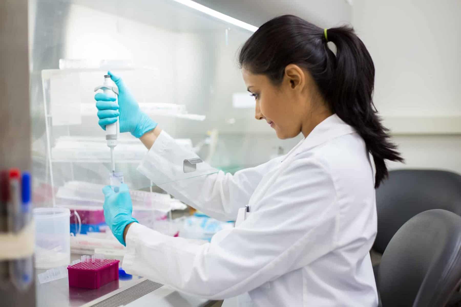 A woman in a white lab coat filling an I.V. fluid bag.