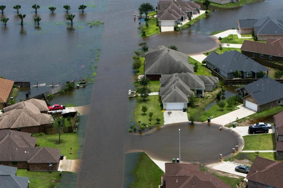 Aerial view of a flooded residential neighborhood with homes and vehicles partially submerged, the climate consequences at stake in the EPA endangerment finding NRDC defended.