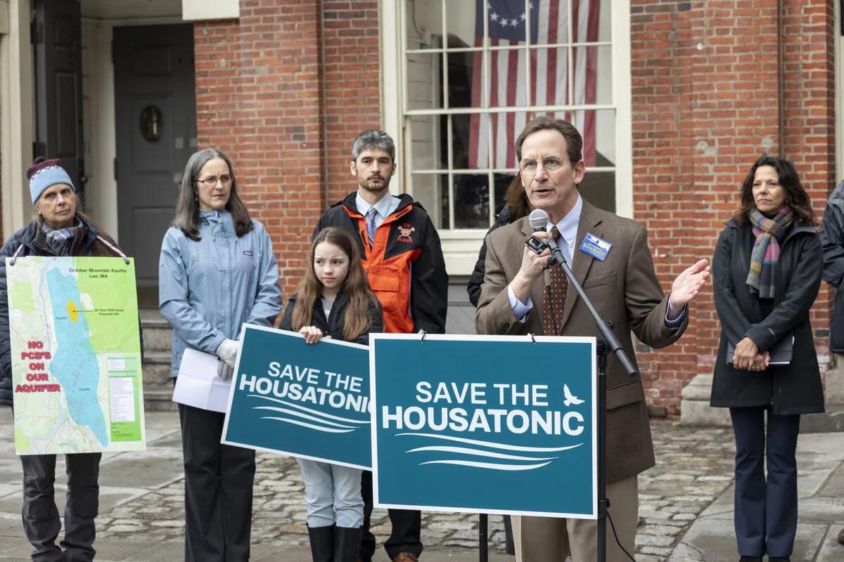 A spokesperson at a microphone flanked by residents holding Save the Housatonic signs, resident leaders serving as the trusted messengers on a legacy pollution cleanup.