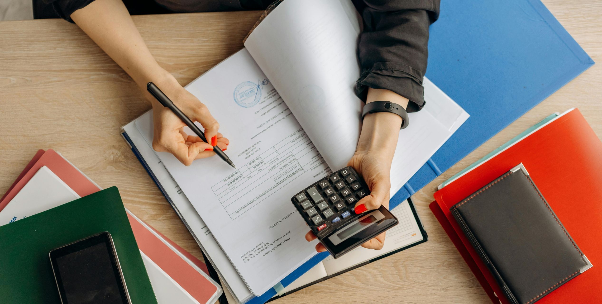 Mappe mit Unterlagen, eine Frau hält einen Taschenrechner in der Hand
