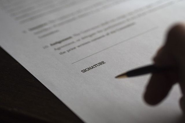 Man sieht eine Hand mit einem Stift auf einem Papier.