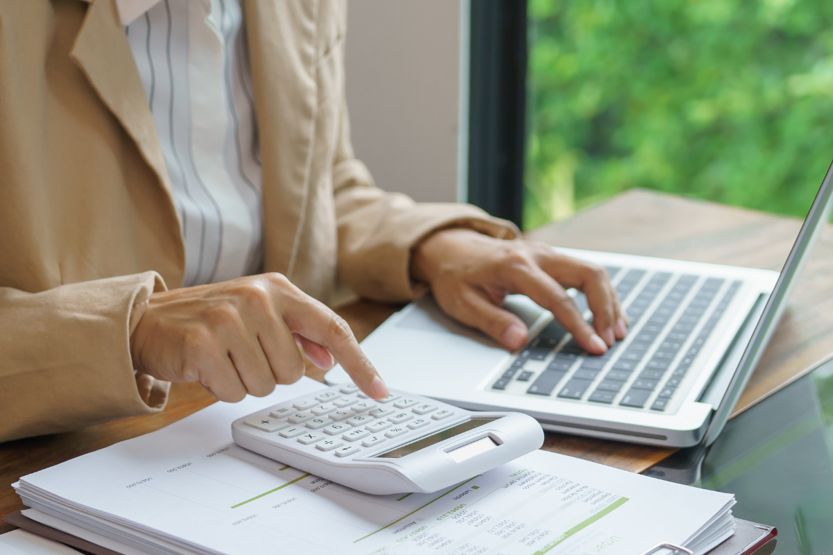 Eine Frau sitzt an einem Laptop mit Taschenrechner