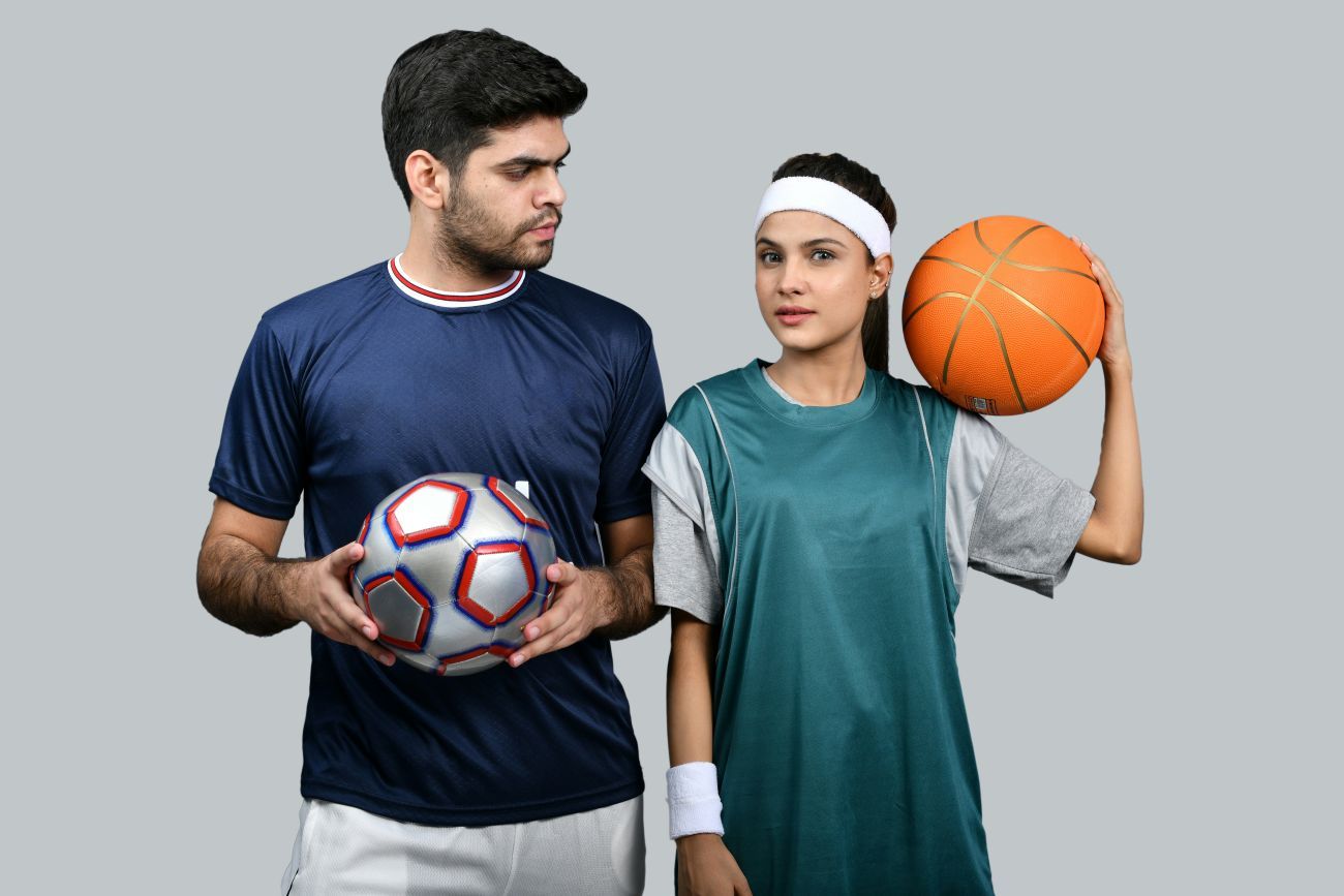 Zwei junge Menschen in Sportkleidung mit Fußball und Basketball als Symbol für vielfältige Online Sportkurse anbieten.
