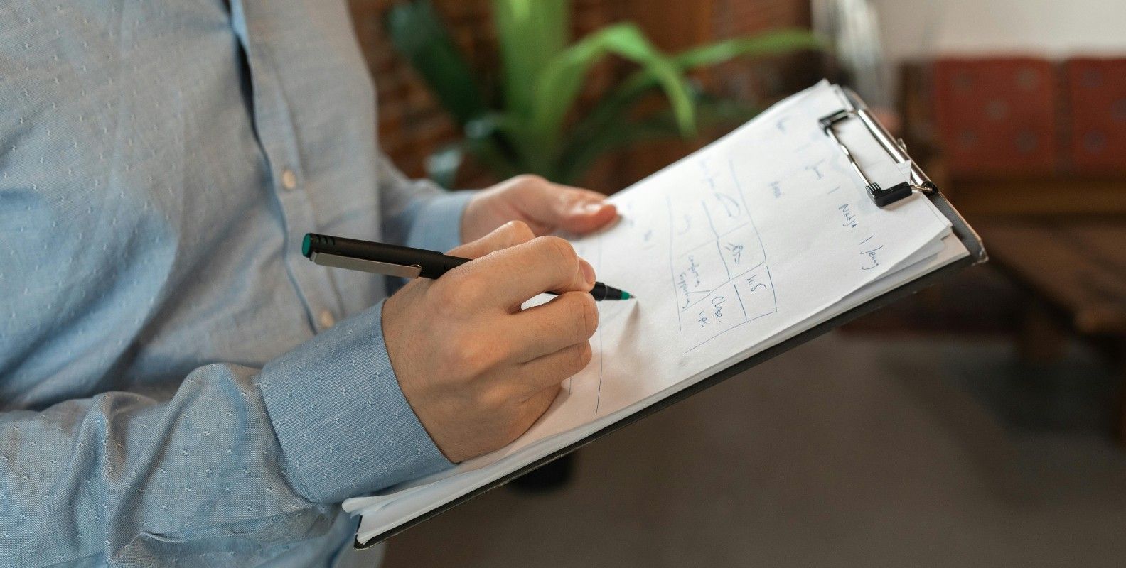 Anwesenheitsliste, Mann hält ein Klemmbrett mit Kugelschreiber