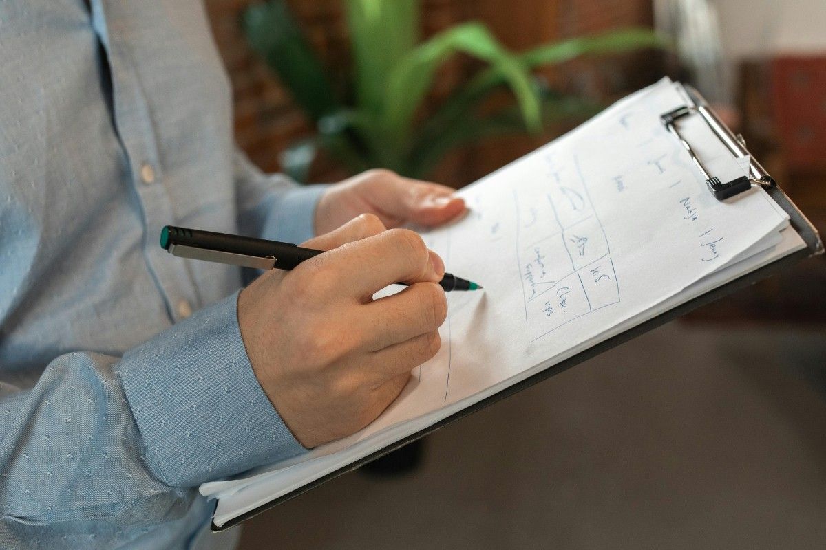 Anwesenheitsliste, Mann hält ein Klemmbrett mit Kugelschreiber