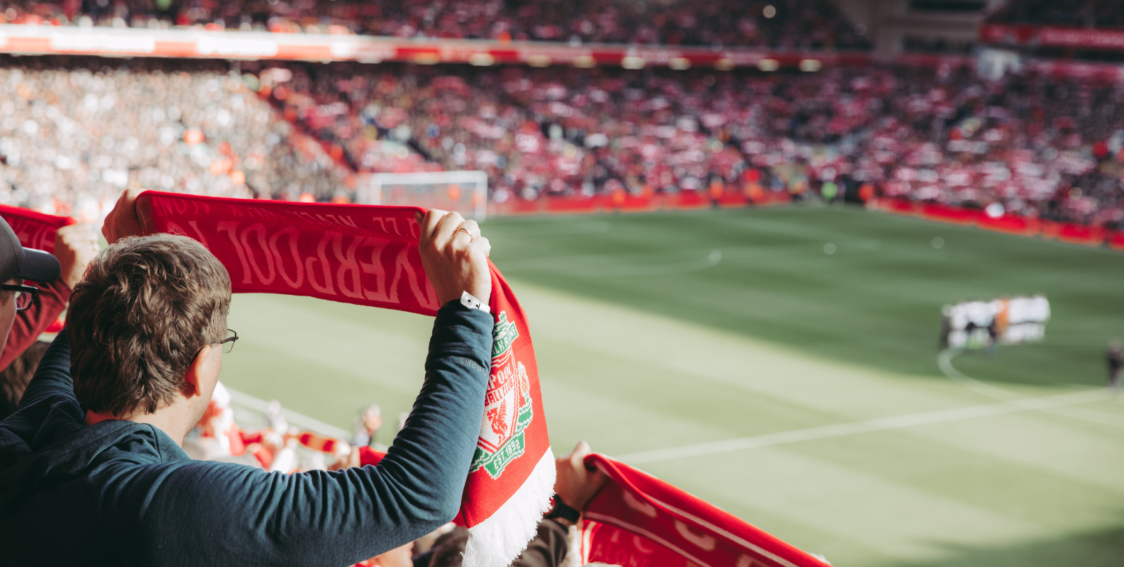 Fan einer Fußballmannschaft hält einen Fan-Schal in die Luft
