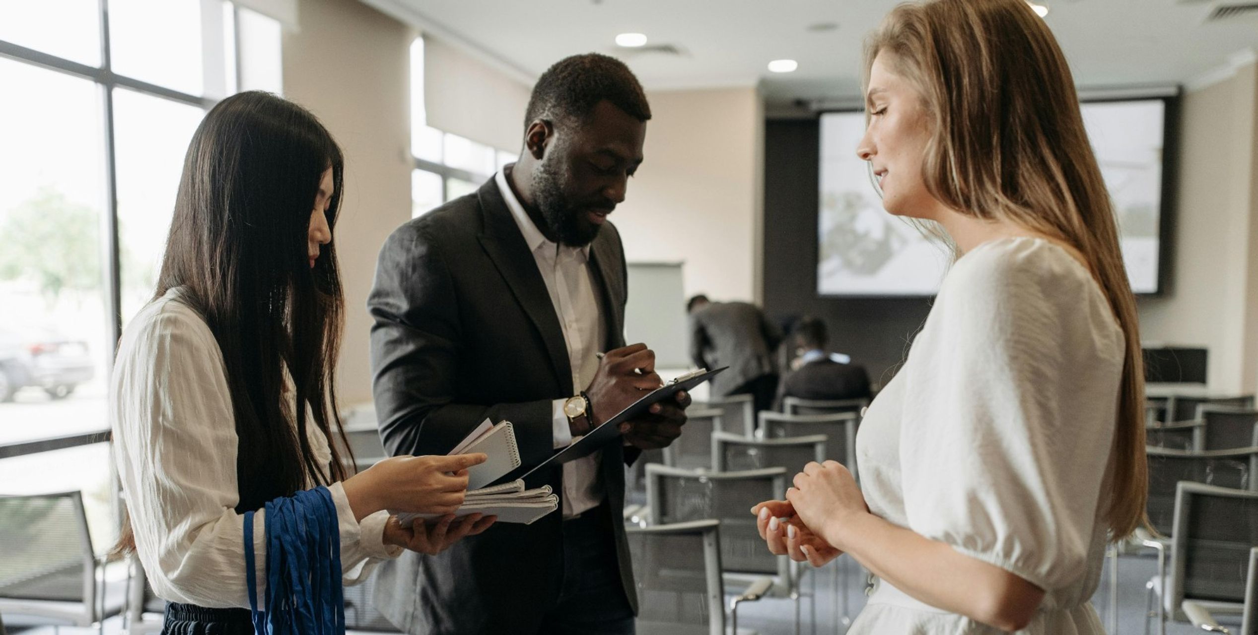 Anwesenheitsliste, Teilnehmerin meldet sich anwesend, Veranstaltungsleiter hält ein Klemmbrett
