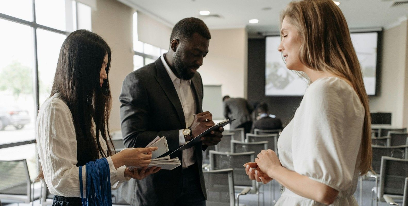 Anwesenheitsliste, Teilnehmerin meldet sich anwesend, Veranstaltungsleiter hält ein Klemmbrett