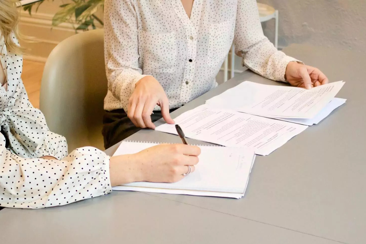 Zwei Frauen sitzen an einem Tisch, Unterlagen