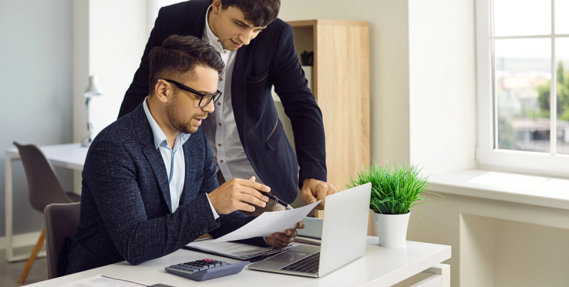 Zwei Männer an einem Tisch mit Laptop