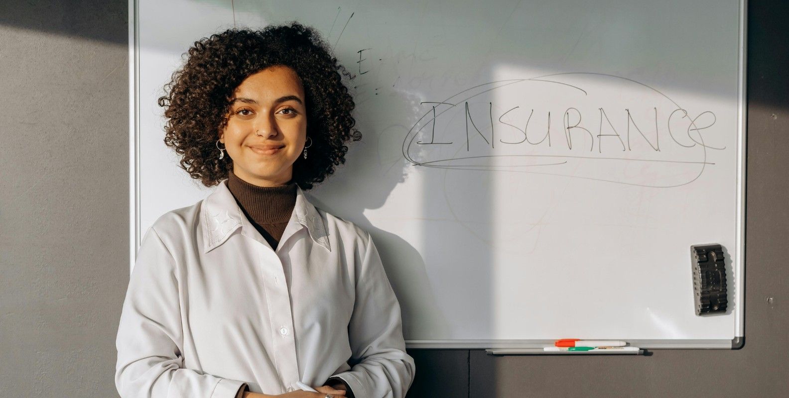 Eine Frau steht vor einer Tafel mit der Aufschrift "Insurance", englisches Wort für "Versicherung".