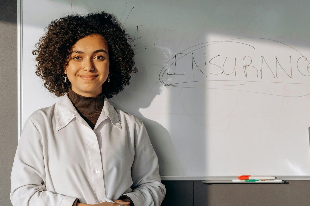Eine Frau steht vor einer Tafel mit der Aufschrift "Insurance", englisches Wort für "Versicherung".