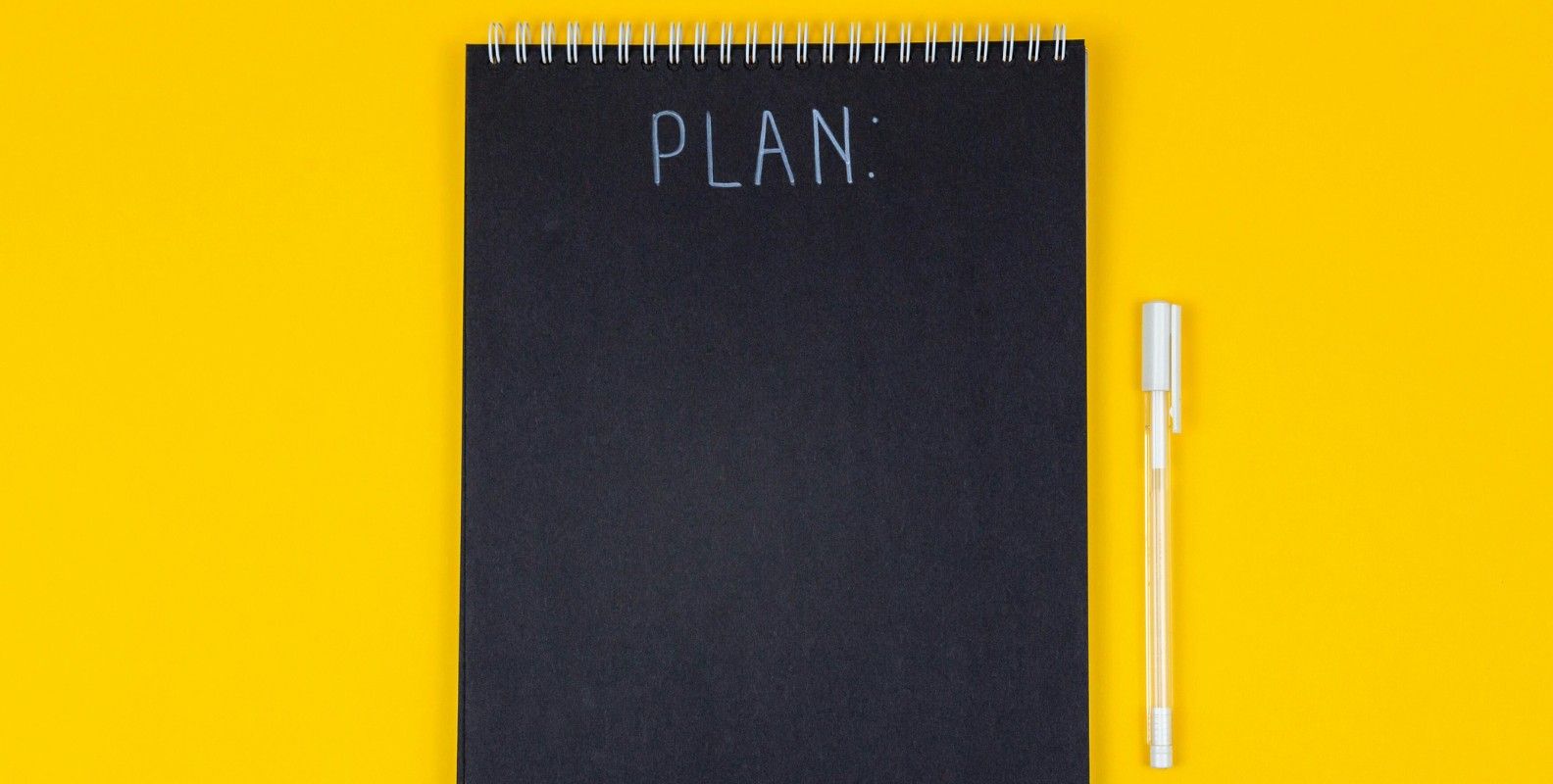 Notizblock mit Schriftzug "Plan" auf gelben Hintergrund mit weißem Stift