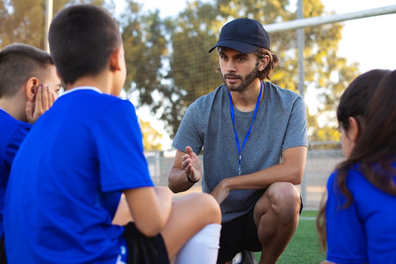 Fußballtrainer unterstützt Kinder beim Training