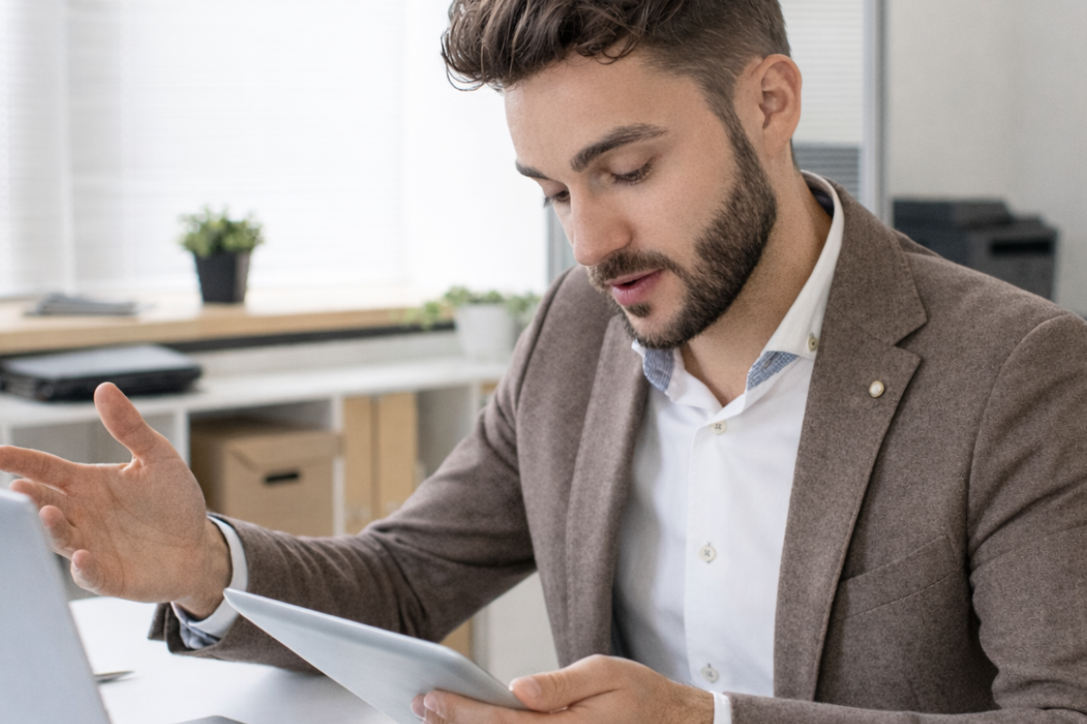 Ein Mann erklärt etwas und hält ein Tablet in der Hand