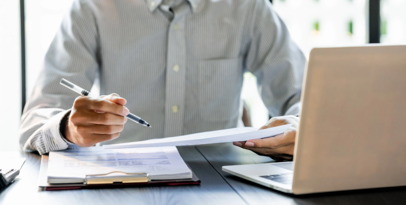 Ein Mann vor dem Laptop mit Unterlagen