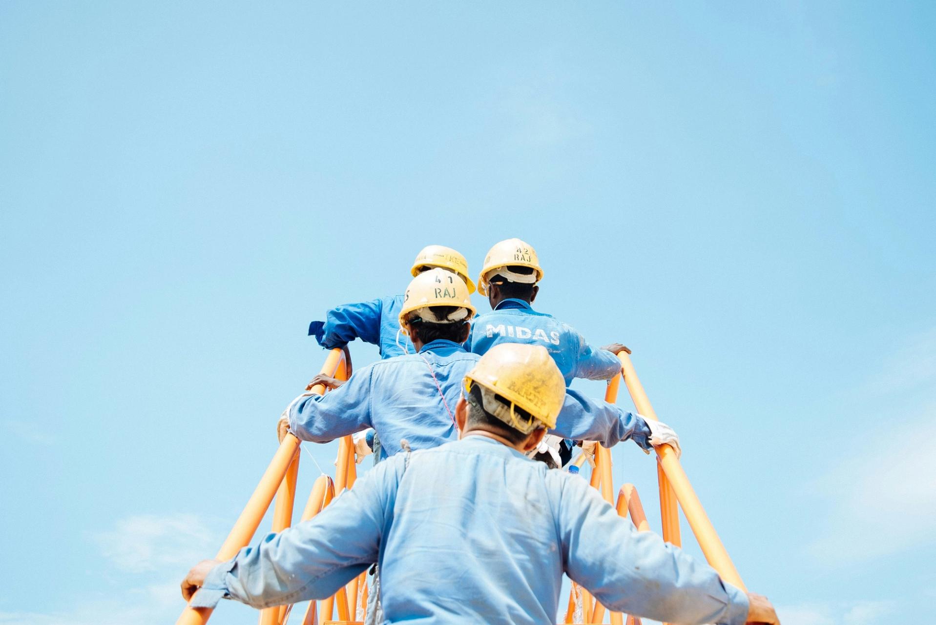 Arbeiter auf Brücke vor blauem Himmel