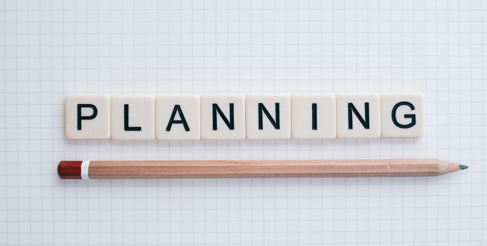 Schriftzug "Planning" mit Stift auf einem karierten Papier