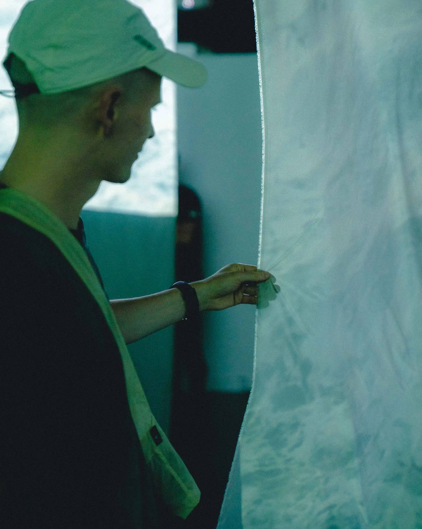Photograph from a Pertex event showing a person interacting with a fabric banner, highlighting the tactile nature of their innovative materials.